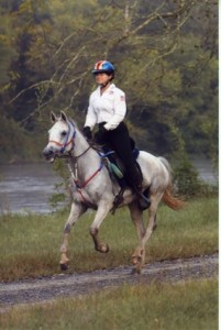 woman riding gray horse on path